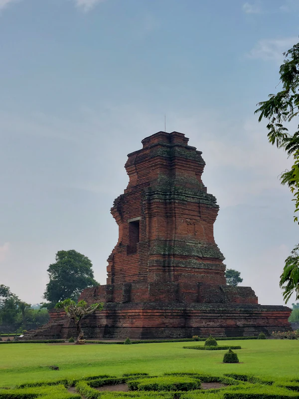 Candi bata merah bergaya Jawa Timur di tengah taman berumput