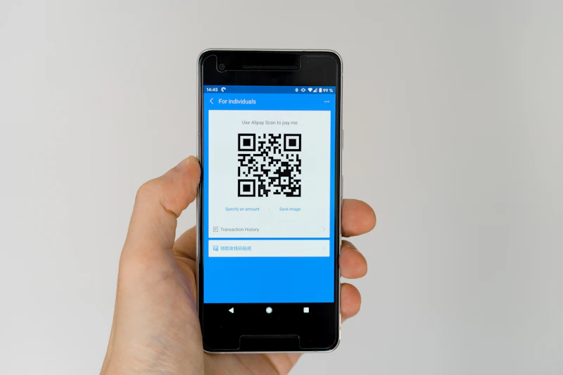 Tangan memegang ponsel yang menampilkan kode QR pembayaran